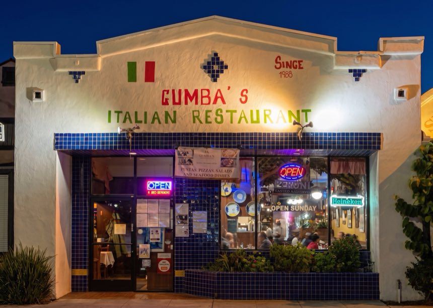 Gumba’s storefront lit up at night, with Since 1988 painted on the wall